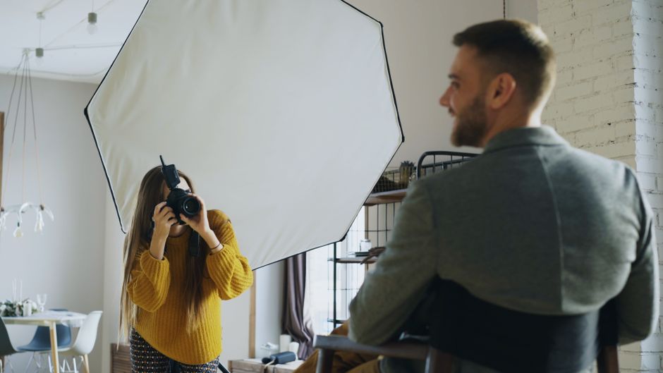 Fotograf s klientkou ve studiu, teplé světlo